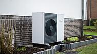 Wärmepumpen-Außengerät vor einem Einfamilienhaus Wärmepumpen-Außengerät vor einem Einfamilienhaus
