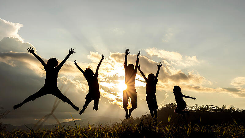 Silhouette group of happy children jumping playing on mountain