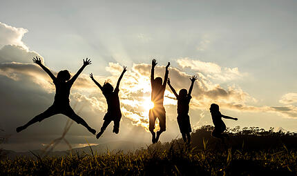 Silhouette group of happy children jumping playing on mountain