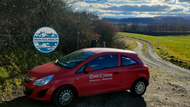 rotes Auto mit Aufschrift Saale Zeitung vor Landschaft
