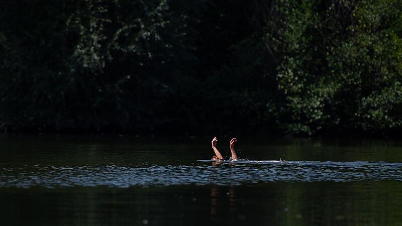 Eine Schwimmerin streckt die Hände aus dem Wasser