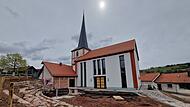 Der historische Kirchturm aus dem 15. Jahrhundert blieb erhalten, der Au&szlig;enbereich rund um den Neubau ist noch Baustelle.