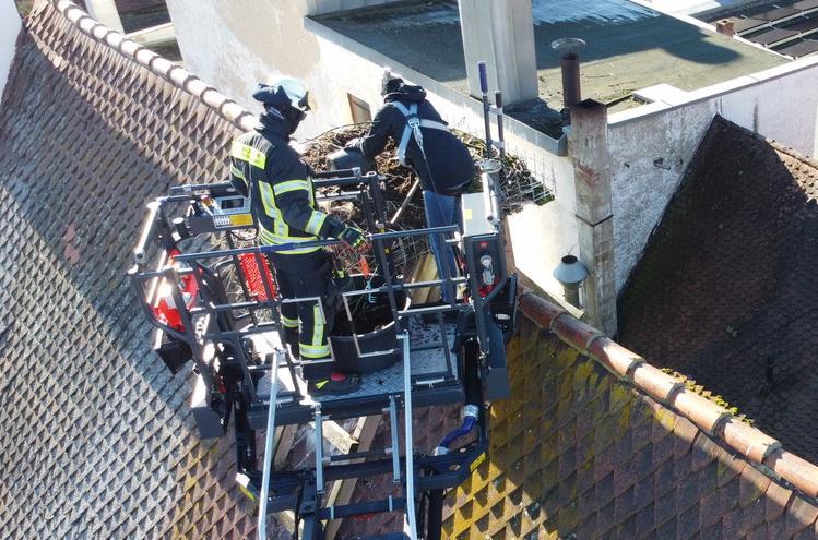 Feuerwehrleute säubern auf dem Dach eines Hauses in der Hauptstraße in Herzogenaurach ein Storchennest. Feuerwehrleute säubern auf dem Dach eines Hauses in der Hauptstraße in Herzogenaurach ein Storchennest.