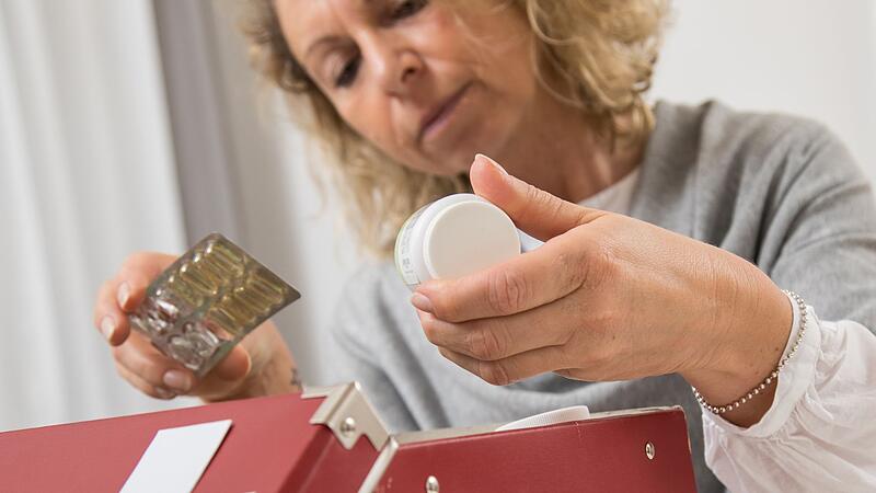 Eine Frau sortiert eine Hausapotheke