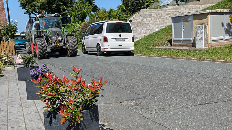 Damit bei Gegenverkehr keine Fahrzeuge über private Hofflächen ausweichen, hilft man sich in Greiendorf mit dicken Holzklötzen oder (wie hier im Bild) mit Blumenkübeln.
