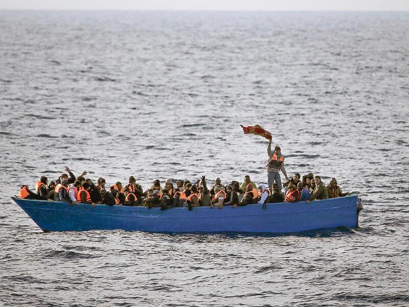 Fl&uuml;chtlinge aus Afrika rufen auf dem Mittelmeer in einem Boot um Hilfe.