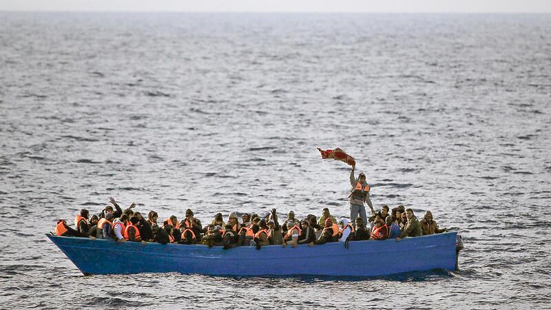 Fl&uuml;chtlinge aus Afrika rufen auf dem Mittelmeer in einem Boot um Hilfe.