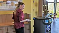 Servicekraft Jennifer Winterstein best&uuml;ckt ihren Roboter-Kollegen Cupy mit Geschirr.