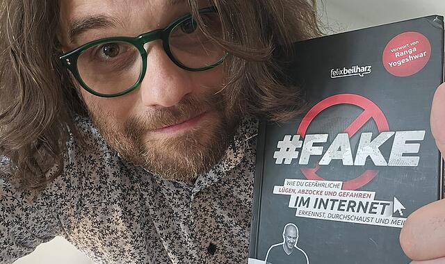 Kabarettist und Autor Florian Herrnleben mit dem Buch "Fake" von Felix Beilharz
