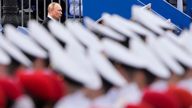 Wladimir Putin (hinten), Pr&auml;sident von Russland, spricht w&auml;hrend der Milit&auml;rparade w&auml;hrend der Feierlichkeiten zum Tag der russischen Marine an der Newa.  Seinen  Krieg f&uuml;hrt erhybrid mit Waffen und mit &ouml;konomischen Methoden.