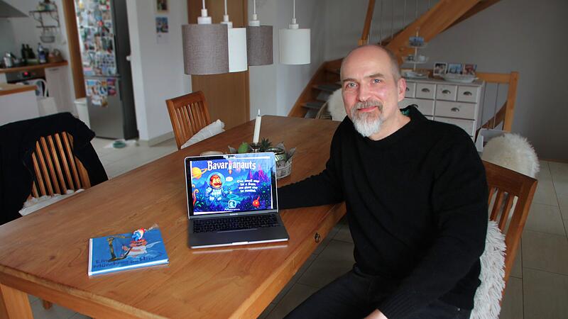 Bavarianauts: Münnerstädter Spieleentwickler Chris Nöth aka McPeppergames Chris Nöth präsentiert seine Idee von Bavarianauts. Daneben das Buch „Ein Münchner im Himmel“, das die Inspiration war.