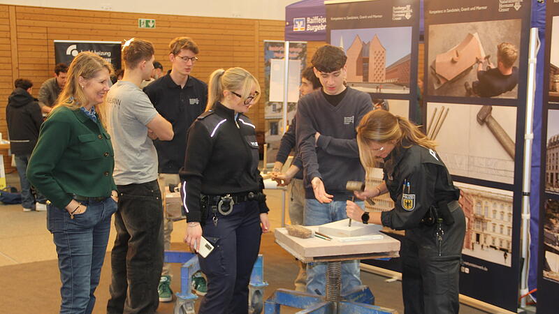 Zwei Polizistinnen versuchen sich am Stand des Bamberger Natursteinwerk Graser an der Steinbearbeitung.