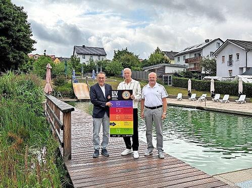 Bürgermeister Thomas Hack (von links), AOK Gesundheitsfachkraft Johannes Kiep und Zweiter Bürgermeister Martin Kaiser freuen sich über die neue UV-Index-Tafel.