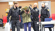 Unter hohen Sicherheitsvorkehrungen und mit Hand- und Fußfesseln wurde ein Angeklagter von Polizeibeamten in die John F. Kennedy-Halle Bamberg gebracht.
