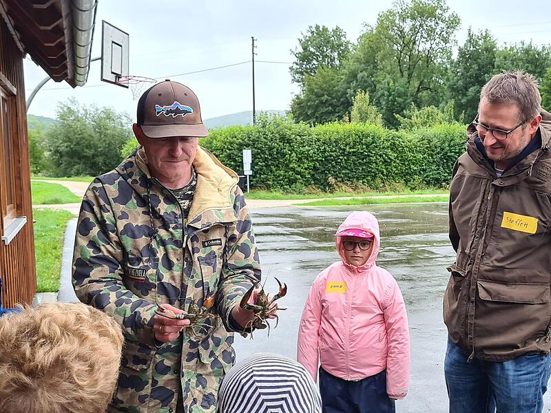 Die Kinder und Steffen Lipfert beobachten die Signalkrebse in den H&auml;nden von Thomas Arnold.Forchheim & Fr&auml;nkische Schweiz