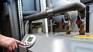 Ein Mann bedient eine Luftwärmepumpe, die im Keller eines Wohnhauses steht.