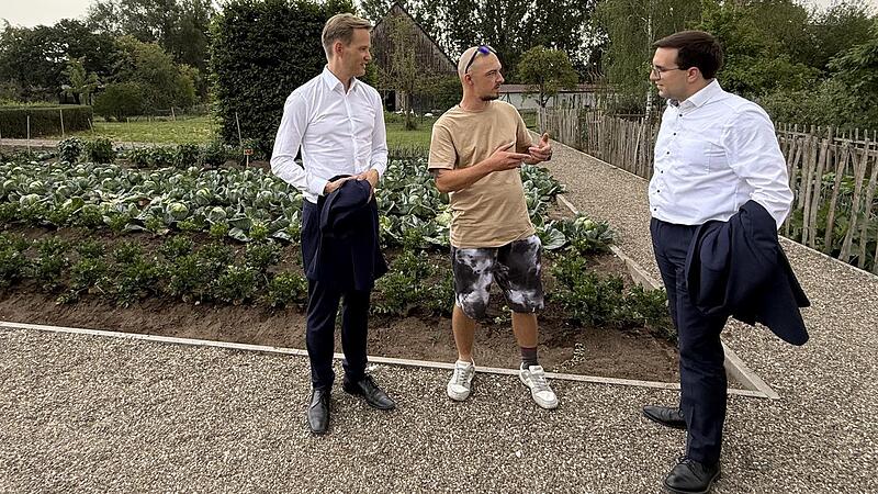 Hendrik Streeck (links) und Konrad K&ouml;rner (rechts) im Gespr&auml;ch mit einem Bewohner, der die landwirtschaftlichen Projekte der Laufer M&uuml;hle in Lauf vorstellt.