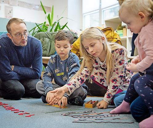 Eine Grundsch&uuml;lerin der L&ouml;wen-Klasse erkl&auml;rt Kindern und Eltern das Montessori-Material.