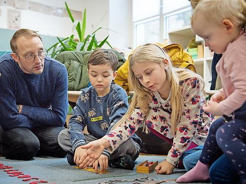 Eine Grundsch&uuml;lerin der L&ouml;wen-Klasse erkl&auml;rt Kindern und Eltern das Montessori-Material.