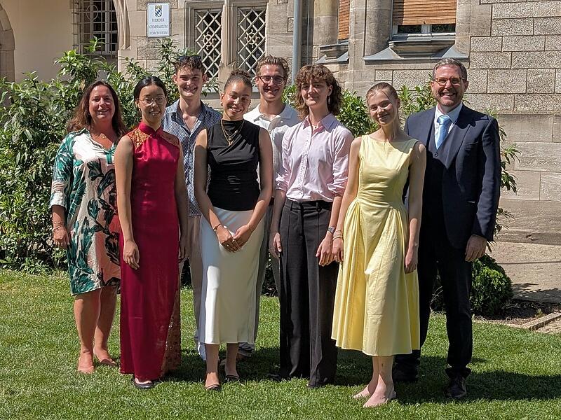 Die besten Absolventen des Abiturjahrgangs 2026 am HGF: (v.l.) Christina Ding (1,2), Joseph Walloch (1,2), Aimie Onwughai (1,0), David Burger (1,2), Amelie Borrmann (1,2), Matilda Geiling (1,2) gemeinsam mit Oberstufenkoordinatorin Yvonne Matzig-Reimann (links) und Schulleiter Dr. Bruno Kuntke (rechts).Forchheim & Fr&auml;nkische Schweiz
