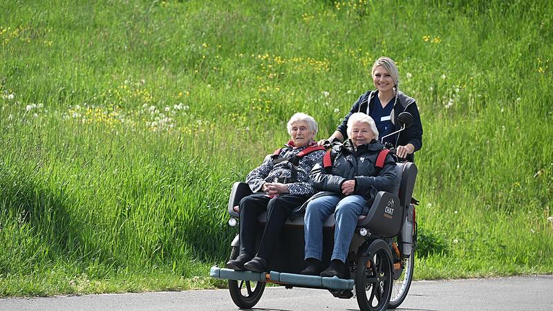 Pflegefachkraft Ilona Zimmermann dreht mit Margarethe Betz und Elisabeth F&ouml;rstel eine Runde in der Senioren-Rikscha.