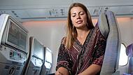 Eine Frau nutzt ihr Smartphone an Bord eines Flugzeugs