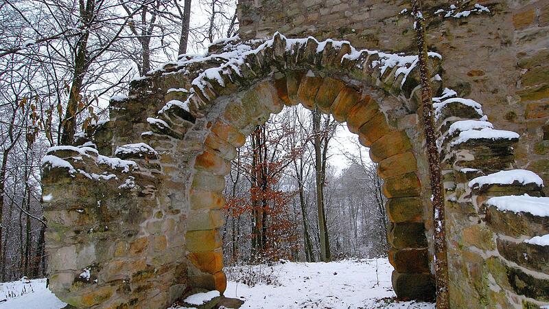 Durch die k&uuml;nstliche Ruine f&auml;llt im verschneiten Wald der Blick auf die Bettenburg &ndash; der Landschaftsgarten ist ein weitum einzigartiger Platz.