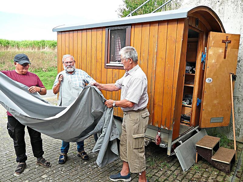 Hans Lyer, Heribert Tr&auml;ger und Paul Hain (von links) bringen an den Kapellenwagen eine Plane an: &bdquo;Als Zelt Gottes unter den Menschen&ldquo;.Marion Kr&uuml;ger-Hundrup