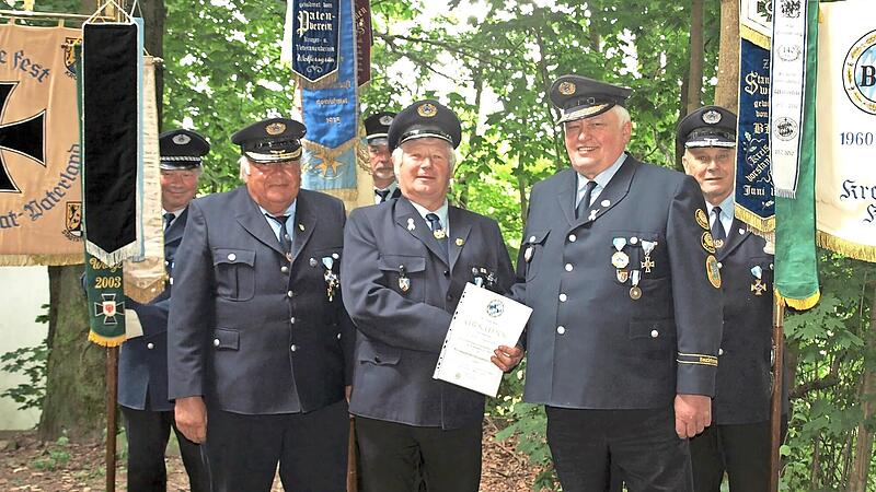 Er hat es wirklich verdient: Georg Spindler (Mitte) wurde von Gottfried Betz (rechts) und Günther Blumenröther (links) mit dem Verbandsverdienststeckkreuz ausgezeichnet. Mit im Bild die Kreis- und Bezirksstandarten sowie die örtliche Fahne