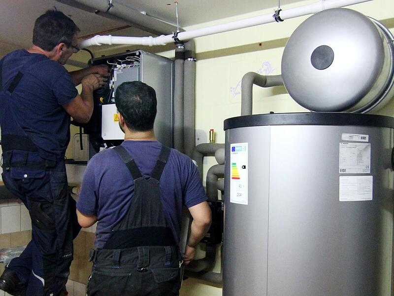 Zwei Handwerker stellen eine installierte Wärmepumpe im Keller ein. Fachkräfte, die sich mit den Geräten auskennen, sind gefragt.Forchheim & Fränkische Schweiz Zwei Handwerker stellen eine installierte Wärmepumpe im Keller ein. Fachkräfte, die sich mit den Geräten auskennen, sind gefragt.Forchheim & Fränkische Schweiz