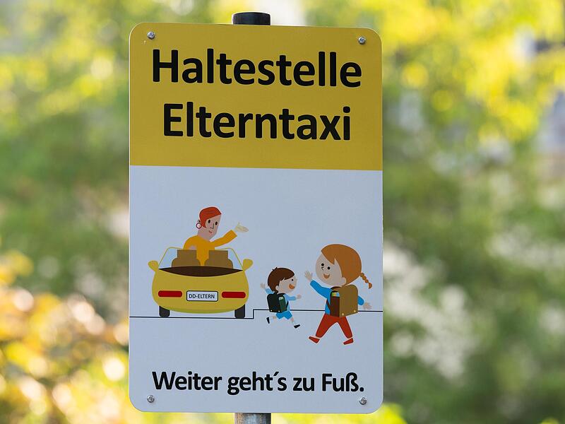 Ein Schild mit der Aufschrift „Haltestelle Elterntaxi“ steht vor einer Dresdner Grundschule.