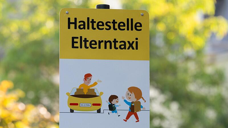 Ein Schild mit der Aufschrift „Haltestelle Elterntaxi“ steht vor einer Dresdner Grundschule.