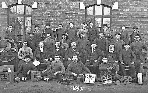 Andreas Flocken (Mitte) und die Belegschaft seiner Landmaschinenfabrik in Coburg, um 1899. Flocken entwickelte ab 1888 eins der ersten deutschen Elektroautos.