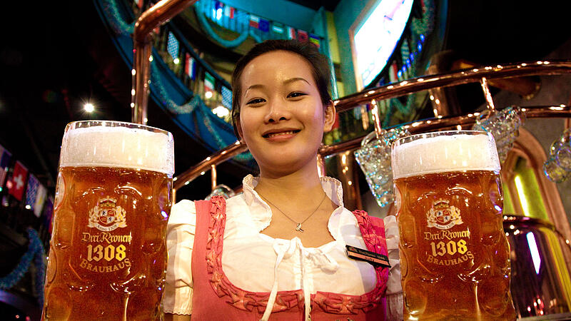 Eine Bedienung im Dirndl serviert Bier des "Drei-Kronen-Brauhauses" in China: Die Urspr&uuml;nge der Marke liegen im kleinen Sche&szlig;litzer Ort Stra&szlig;giech im Landkreis Bamberg