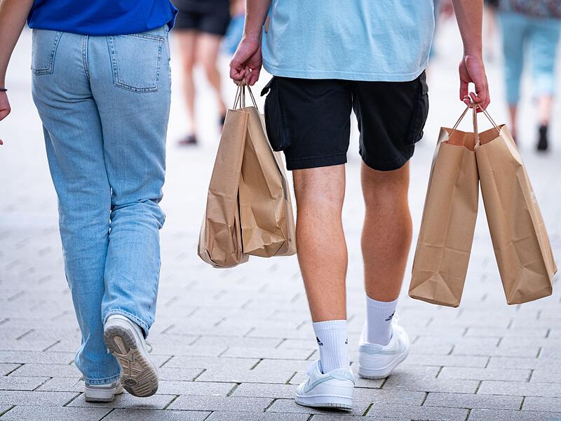 Menschen in einer Fußgängerzone mit Papiertüten beim Shopping