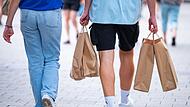 Menschen in einer Fußgängerzone mit Papiertüten beim Shopping