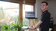 Adrian Kraus mit dem ergonomisch geformten, höhenverstellbaren  Schreibtischaufsatz fürs Laptop.