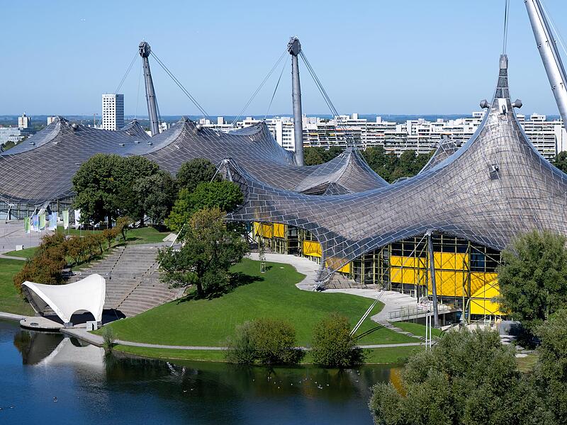 Die Olympiahalle (l) und die Schwimmhalle der olympischen Sommerspiele von 1972 sind im Olympiapark zu sehen. Am 26. Oktober 2025 findet der Bürgerentscheid zur Bewerbung der Stadt München um Olympische und Paralympische Spiele statt.