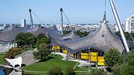 Die Olympiahalle (l) und die Schwimmhalle der olympischen Sommerspiele von 1972 sind im Olympiapark zu sehen. Am 26. Oktober 2025 findet der Bürgerentscheid zur Bewerbung der Stadt München um Olympische und Paralympische Spiele statt.