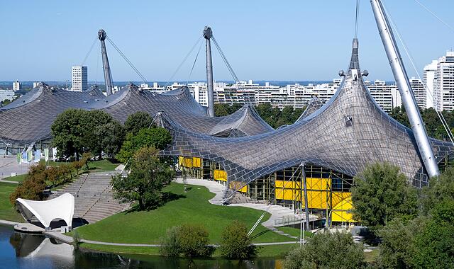 Die Olympiahalle (l) und die Schwimmhalle der olympischen Sommerspiele von 1972 sind im Olympiapark zu sehen. Am 26. Oktober 2025 findet der Bürgerentscheid zur Bewerbung der Stadt München um Olympische und Paralympische Spiele statt.