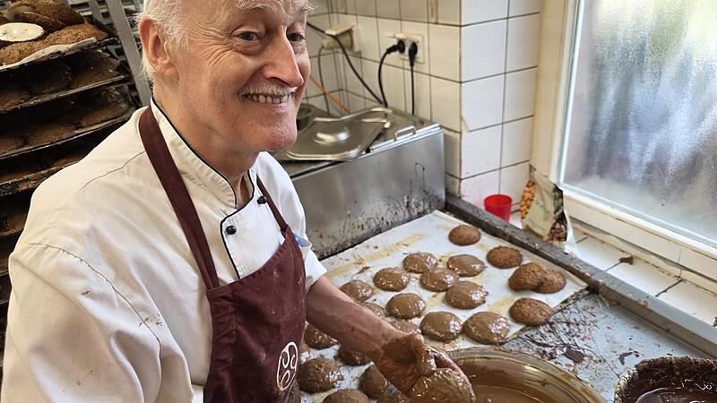 Ein Mitarbeiter der B&auml;ckerei D&uuml;ll bestreicht die Lebkuchen von Hand mit Schokolade.