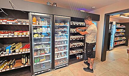 Sascha Klau&szlig;ner sortiert Ware in ein Regal seines 24-Stundenladens in Kalchreuth.