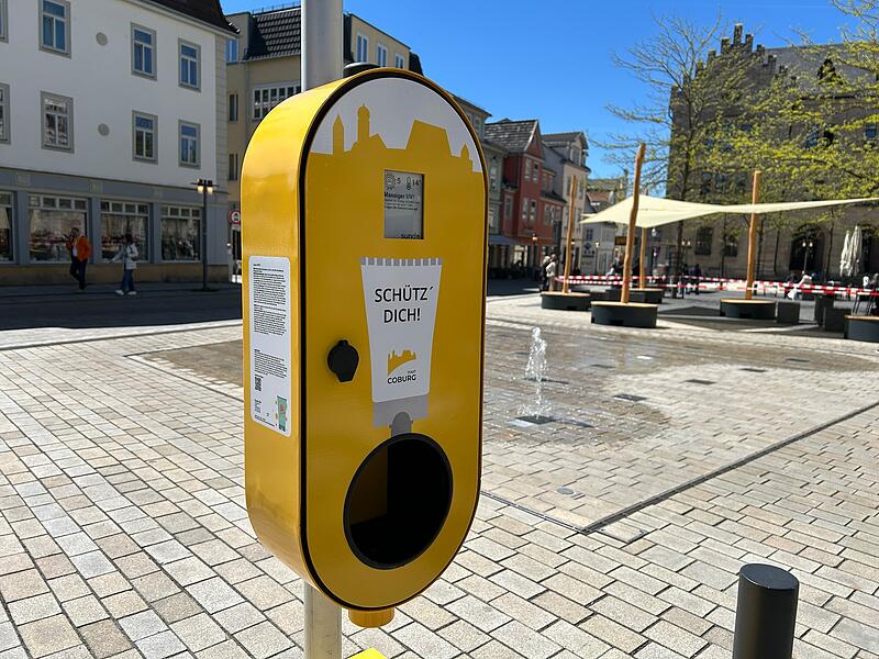 In diesem Spender auf dem Albertsplatz befindet sich Sonnencreme mit dem Lichtschutzfaktor 50 plus; &uuml;ber s&auml;mtliche Inhaltsstoffe kl&auml;rt ein Hinweisschild auf. Im Hintergrund ist das neue Sonnensegel zu sehen.