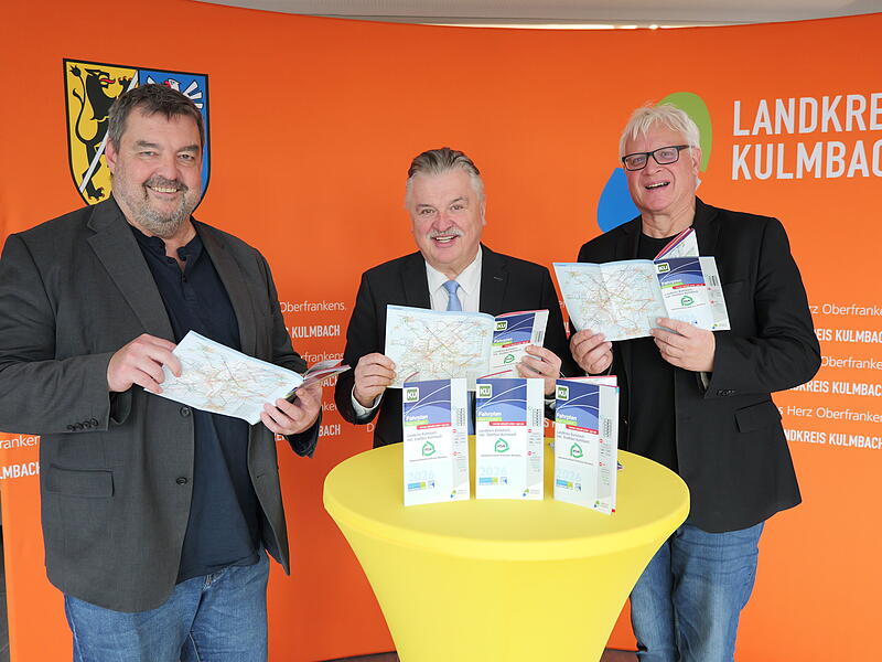 Vorstellung Fahrplanheft Landkreis Kulmbach 2026 Kompakt und informativ - Volker Griesbach (links) und Michael Beck (rechts) vom Mobilitäts- und GIS-Management werfen mit Landrat Klaus Peter Söllner einen Blick in das druckfrische Fahrplanheft des Landkreises für 2026.