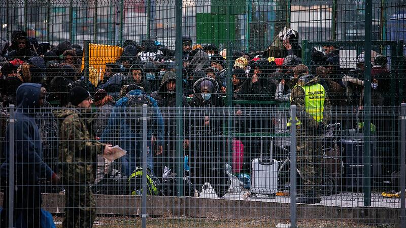 Polen, Medyka: Menschen warten am Grenz&uuml;bergang hinter einem Tor auf die Einreise nach Polen.