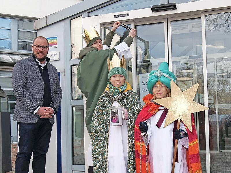 Sch&ouml;ner Start ins neue Jahr: Die Sternsinger Josias, Oscar und Ida bringen den Dreik&ouml;nigs-Segen am Eingang des Landratsamtes an. Links Landrat Sebastian Straubel.