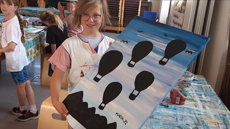 Erfreut zeigt Maria ihr gelungenes Gemälde mit den schwarzen Heissluftballons. Erfreut zeigt Maria ihr gelungenes Gemälde mit den schwarzen Heissluftballons.