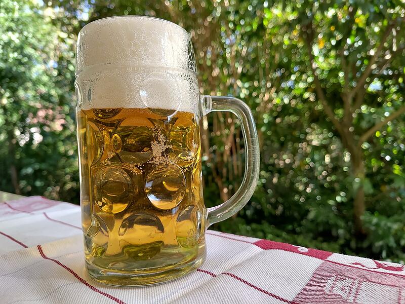 0,5-Liter-Glaskrug auf einem Gartentisch, gef&uuml;llt mit alkoholfreiem hellen Bier.