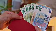 Eine Frau hält einen Umschlag mit Euro-Banknoten
