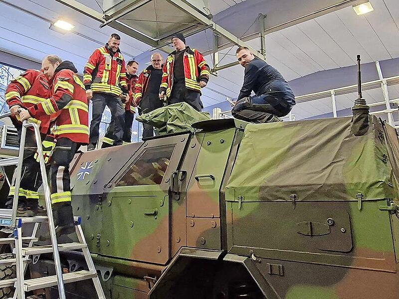 Die Feuerwehrleute schauen sich die Fahrzeuge an.